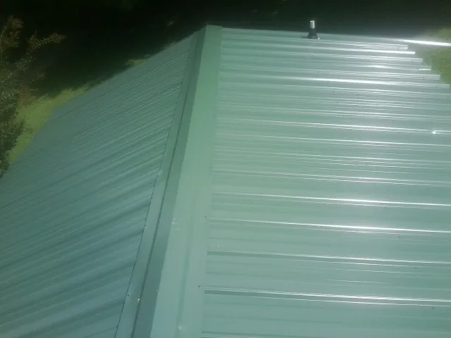 New green metal panels meeting at the ridge of a roof — Flat Roof Repair work by our crew in Aberdeen